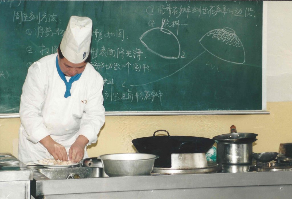Kokkemesterlæreren underviser i tilberedningen af kylling og grønt i sur/sød sauce