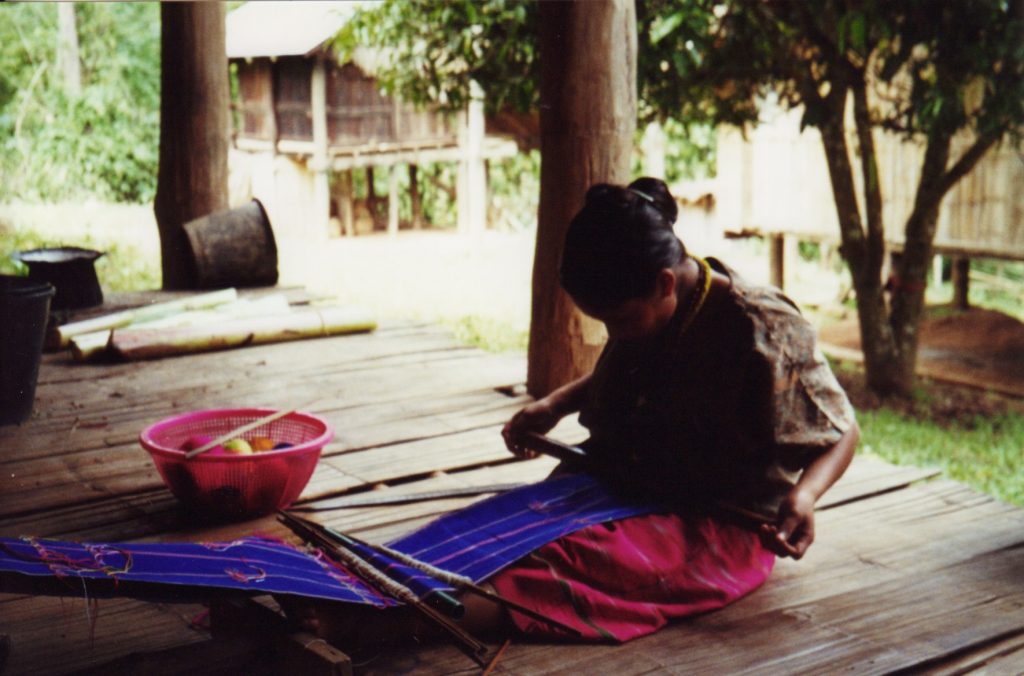 En Karen-kvinde væver stoffer i stammens farver